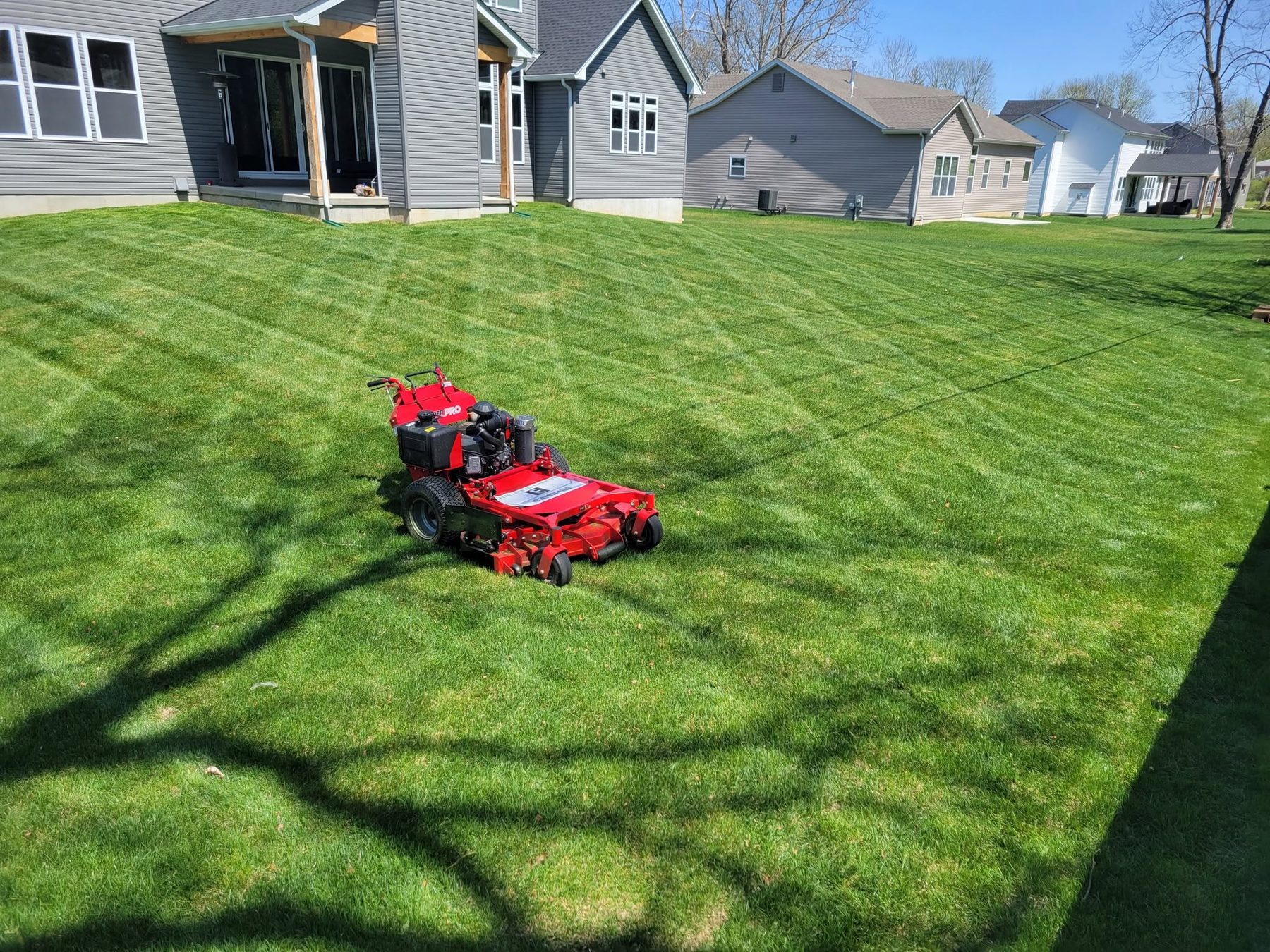 A red mower on a freshly striped lawn in front of the houses
